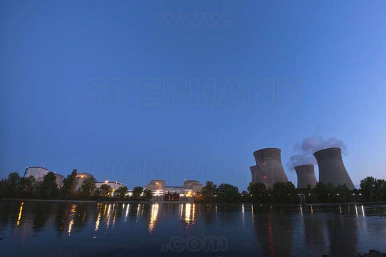 Centrale nucléaire du Bugey : Vue nocturne des installations depuis les bords de la rive gauche du Rhône. De gauche à droite : les réacteurs 1 (d'une conception différente et plus ancienne, il est à l'arrêt définitif depuis 1996), 2, 3, 4 et 5, puis les quatre tours aéroréfrigérantes (hauteur 128 m., largeur 104 m.).