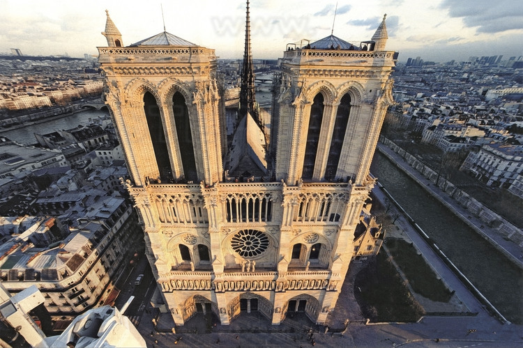 Vue générale de la façade principale (ouest) de la Cathédrale Notre Dame de Paris au soleil couchant. En arrière plan, à gauche et à droite, les quais de la Seine.
