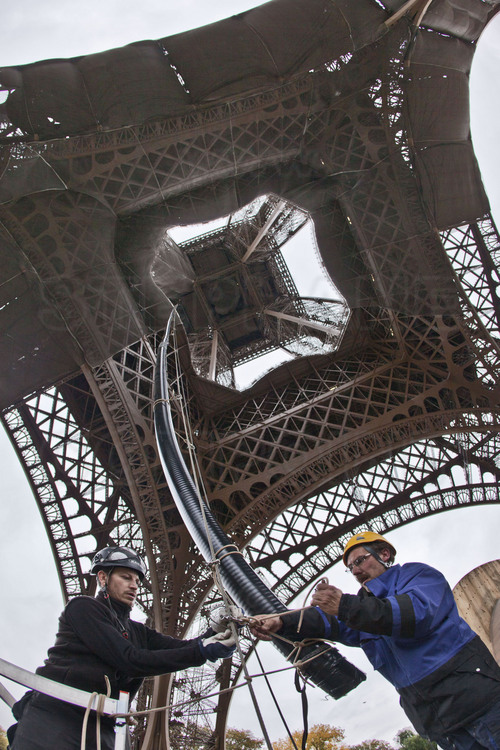 Depuis le parvis de la tour Eiffel, les techniciens de TDF hissent le feeder (liaison coaxiale entre la sortie de l’émetteur et des antennes d’émission) guidé via deux câbles d’acier tendus entre le sol et le 2ème étage.