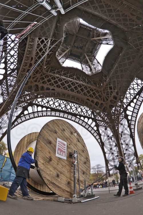 Depuis le parvis de la tour Eiffel, les techniciens de TDF hissent le feeder (liaison coaxiale entre la sortie de l’émetteur et des antennes d’émission) guidé via deux câbles d’acier tendus entre le sol et le 2ème étage.