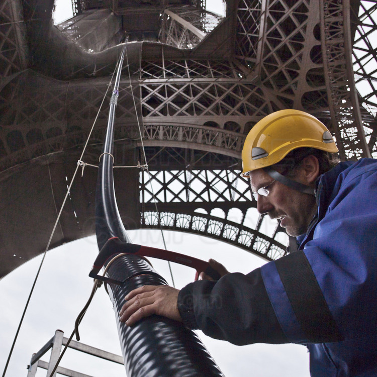 Sur le parvis de le tour Eiffel, hissage et découpe du feeder (liaison coaxiale entre la sortie de l’émetteur et des antennes d’émission) guidé via deux câbles d’acier tendus entre le sol et le 2ème étage.