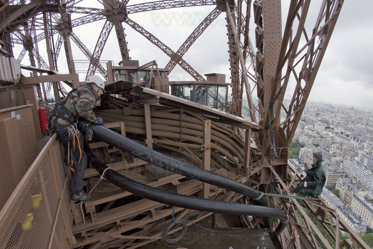 Préparation du feeder (liaison coaxiale entre la sortie de l’émetteur et des antennes d’émission) sur la terrasse du 2ème étage de la tour Eiffel : ce dernier, hissé par l'extérieur de la terrasse, est ramené vers son cheminement définitif entre le 2ème et le 3ème étage.