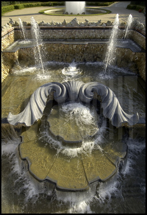 Au bosquet des Trois Fontaines, les jets d'eau animent un décor où le végétal est roi. Une gigantesque coquille Saint Jacques en plomb, à la structure en béton armé, trône au centre de la façade supérieure.