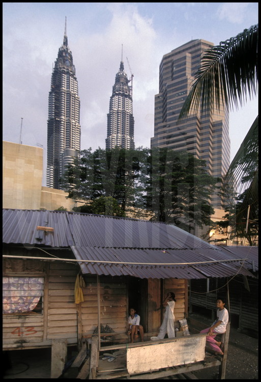 Les Petronas Towers vues depuis l'Ouest. Au premier plan, une des nombreuses baraques de fortunes où viennent habiter les ouvriers des grands chantiers de la ville.