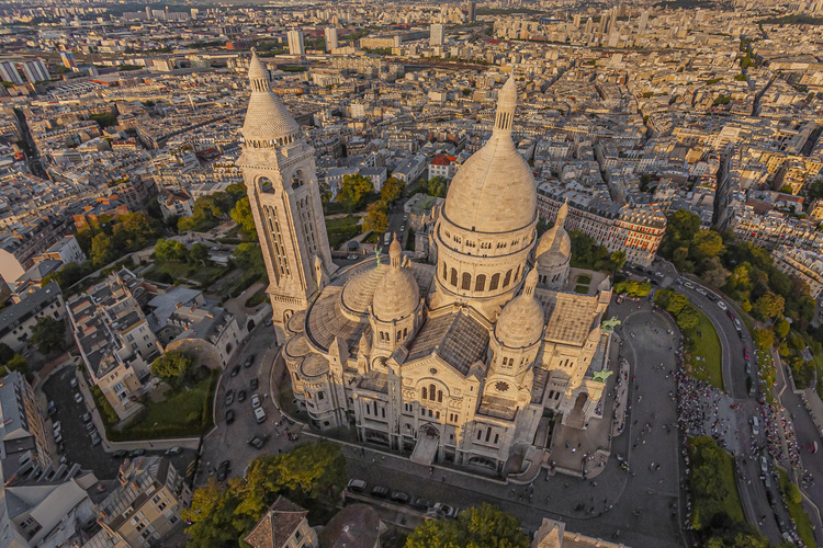 Paris (75) - La butte Montmartre et la basilique du Sacré Coeur vus depuis le Sud Est. Située au sommet de la butte Montmartre, la basilique du Sacré-Cœur, est l'un des édifices religieux majeurs de Paris. Sa construction est décidée en 1870 (juste après la guerre franco-allemande) lors du vœu national d'Alexandre Legentil et Hubert Rohault de Fleury, et sera achevée en 1914. Sa situation à 130 m d'altitude près de l'un des points culminants de Paris, et son dôme qui s'élève à 83 mètres, la rendent visible de très loin. Avec près de onze millions de pèlerins et visiteurs par an, c'est le deuxième monument religieux parisien le plus visité après la cathédrale Notre-Dame de Paris. // France - Paris (75) - The Montmartre hill and the Sacré Coeur basilica seen from the South East. Located at the top of the Montmartre hill, the Sacré-Coeur basilica is one of the major religious buildings in Paris. Its construction was decided in 1870 (just after the Franco-German war) during the national wish of Alexandre Legentil and Hubert Rohault de Fleury, and will be completed in 1914. Its location at 130 m above sea level near one of the points highlights of Paris, and its dome which rises to 83 meters, make it visible from far away. With nearly eleven million pilgrims and visitors a year, it is the second most visited Parisian religious monument after Notre-Dame de Paris cathedral.