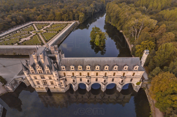 Val de Loire - Indre et Loire (37) - Château de Chenonceau : Vue aérienne depuis l'ouest, au soleil couchant. Au premier plan et au centre, le Cher. A gauche, l'avant-cour et le jardin de Diane de Poitiers. Bâti sur les plans d’un palais vénitien au XVIe siècle, le château de Chenonceau, doté de cinq arches enjambant élégamment le Cher, est l’unique château-pont au monde. Surnommé le château des Dames, son histoire a été marquée, entre autres, par celle de cinq femmes, grandes séductrices ou femmes de pouvoir : Diane de Poitiers (1499 - 1566), Catherine de Médicis (1519 - 1589), Louise de Lorraine (1553 - 1601), Gabrielle d’Estrées (1573 - 1599) et Louise Dupin (1706 - 1799). // France - Loire valley - Indre et Loire (37)  - Castle of Chenonceau : Aerial view from the west, at sunset. On foreground and in center, the Cher. On the left, the garden of Catherine de Medicis, the forecourt, the tower of Marques and the garden of Diane de Poitiers. On background left, the slopes of the village of Chenonceaux. Built on the plans of a Venetian palace in the sixteenth century, Chenonceau Castle, with five arches spanning the Cher River, is the only bridge-castle in the world. Nicknamed the Ladies' Castle, its history has been marked, among others, by five women, great seductresses or women of power: Diane de Poitiers (1499 - 1566), Catherine de Medici (1519 - 1589), Louise de Lorraine ( 1553 - 1601), Gabrielle d'Estrées (1573 - 1599) and Louise Dupin (1706 - 1799).