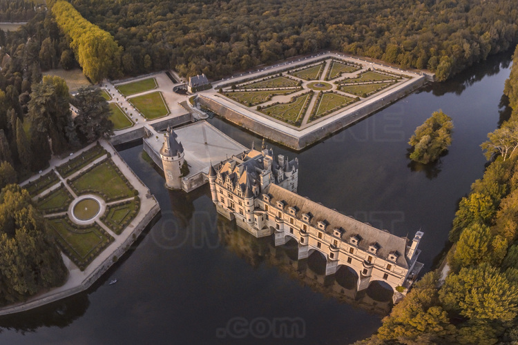 Val de Loire - Indre et Loire (37) - Château de Chenonceau : Vue aérienne depuis le sud ouest, au soleil couchant. Au premier plan, le Cher. Au second plan de gauche à droite, le jardin de Catherine de Medicis, l'avant-cour, la tour des Marques et le jardin de Diane de Poitiers. Bâti sur les plans d’un palais vénitien au XVIe siècle, le château de Chenonceau, doté de cinq arches enjambant élégamment le Cher, est l’unique château-pont au monde. Surnommé le château des Dames, son histoire a été marquée, entre autres, par celle de cinq femmes, grandes séductrices ou femmes de pouvoir : Diane de Poitiers (1499 - 1566), Catherine de Médicis (1519 - 1589), Louise de Lorraine (1553 - 1601), Gabrielle d’Estrées (1573 - 1599) et Louise Dupin (1706 - 1799). // France - Loire valley - Indre et Loire (37)  - Castle of Chenonceau : Aerial view from the southwest, at sunset. On foreground, the Cher river. On background from left to right, the garden of Catherine de Medicis, the forecourt, the Marques Tower and the garden of Diane de Poitiers. Built on the plans of a Venetian palace in the sixteenth century, Chenonceau Castle, with five arches spanning the Cher river, is the only bridge-castle in the world. Nicknamed the Ladies' Castle, its history has been marked, among others, by five women, great seductresses or women of power : Diane de Poitiers (1499 - 1566), Catherine de Medici (1519 - 1589), Louise de Lorraine ( 1553 - 1601), Gabrielle d'Estrées (1573 - 1599) and Louise Dupin (1706 - 1799).