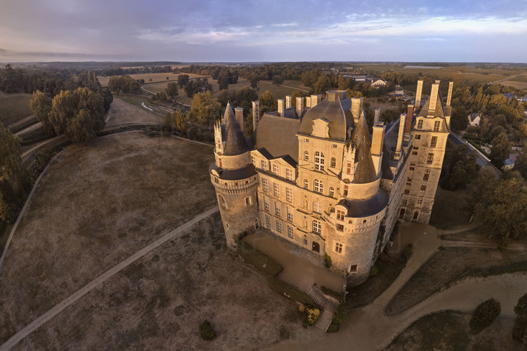 Val de Loire - Maine et Loire (49) - Château de Brissac : Vue aérienne depuis le nord-est, au soleil levant. En arrière plan et à gauche, le parc (70 hectares). Plus haut château de France avec ses 48 mètres de hauteur, 7 étages et 204 pièces, il mérite bien son surnom de « Géant du Val de Loire ». Acquis en 1502, par René de Cossé, 1er seigneur de Brissac, il est aujourd'hui la résidence du 13ème duc de Brissac. // France - Loire valley - Maine et Loire (49)  - Castle of Brissac : Aerial view from the north-east at rising sun. On background and left, the park (70 hectares). Highest castle in France with 48 meters high, 7 floors and 204 rooms, it deserves its nickname 