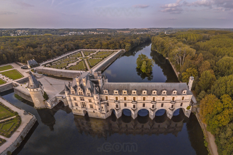 Val de Loire - Indre et Loire (37) - Château de Chenonceau : Vue aérienne depuis l'ouest, au soleil couchant. Au premier plan et au centre, le Cher. A gauche, l'avant-cour, la tour des Marques et le jardin de Diane de Poitiers. En arrière plan à gauche, les coteaux du village de Chenonceaux. Bâti sur les plans d’un palais vénitien au XVIe siècle, le château de Chenonceau, doté de cinq arches enjambant élégamment le Cher, est l’unique château-pont au monde. Surnommé le château des Dames, son histoire a été marquée, entre autres, par celle de cinq femmes, grandes séductrices ou femmes de pouvoir : Diane de Poitiers (1499 - 1566), Catherine de Médicis (1519 - 1589), Louise de Lorraine (1553 - 1601), Gabrielle d’Estrées (1573 - 1599) et Louise Dupin (1706 - 1799). // France - Loire valley - Indre et Loire (37)  - Castle of Chenonceau : Aerial view from the west, at sunset. On foreground and in center, the Cher. On the left, the garden of Catherine de Medicis, the forecourt, the tower of Marques and the garden of Diane de Poitiers. On background left, the slopes of the village of Chenonceaux. Built on the plans of a Venetian palace in the sixteenth century, Chenonceau Castle, with five arches spanning the Cher River, is the only bridge-castle in the world. Nicknamed the Ladies' Castle, its history has been marked, among others, by five women, great seductresses or women of power: Diane de Poitiers (1499 - 1566), Catherine de Medici (1519 - 1589), Louise de Lorraine ( 1553 - 1601), Gabrielle d'Estrées (1573 - 1599) and Louise Dupin (1706 - 1799).