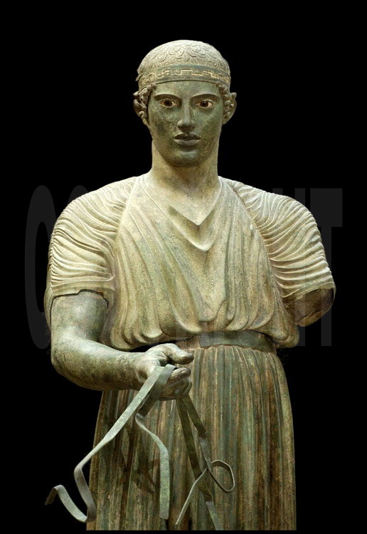 Discovered at the beginning of the century by the archeological team of the French School of Athens, this charioteer of a bronze quadriga was at the entrance of Apollo’s temple in Delphi.  This work of art is dedicated to Polyzalos, the tyrant of Gela, after his victory in the Delphi Games (Pythic Games).  The young man is holding the reins and wearing the victory headband around his forehead, decorated with a silver meander.  478 B.C.  Archeological Museum of Delphi.