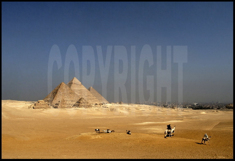Depuis le désert de Libye, à l’Ouest du Caire, la célèbre vue dite des « neufs pyramides » : au premier plan, les trois petites pyramides des reines de Mykérinos. Derrière, les pyramides de Mykérinos, Khephren et Kheops. A droite de cette dernière, les trois petites pyramides des reines de Kheops. Toutes sont de la IVème dynastie. En arrière plan à droite, la ville du Caire.