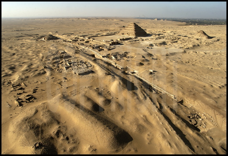 Vue aérienne de la nécropole de Sakkarah Nord depuis le Sud-Est. Au premier plan, les vestiges du monastère de Saint Jérémie (à gauche) et la chaussée d’Ounas. Au second plan, la pyramide d’Ounas (Vème dynastie), le complexe funéraire de Djoser (IIIème dynastie) et la pyramide d’Ouserkaf (Vème dynastie).