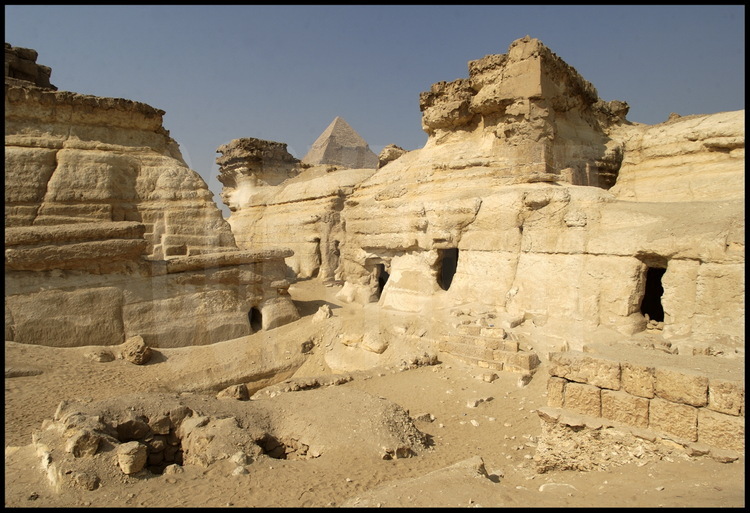 Tombes troglodytes dans la partie Sud de la nécropole de Gizeh. En arrière plan, le sommet de la pyramide de Khephren (IVème dynastie).