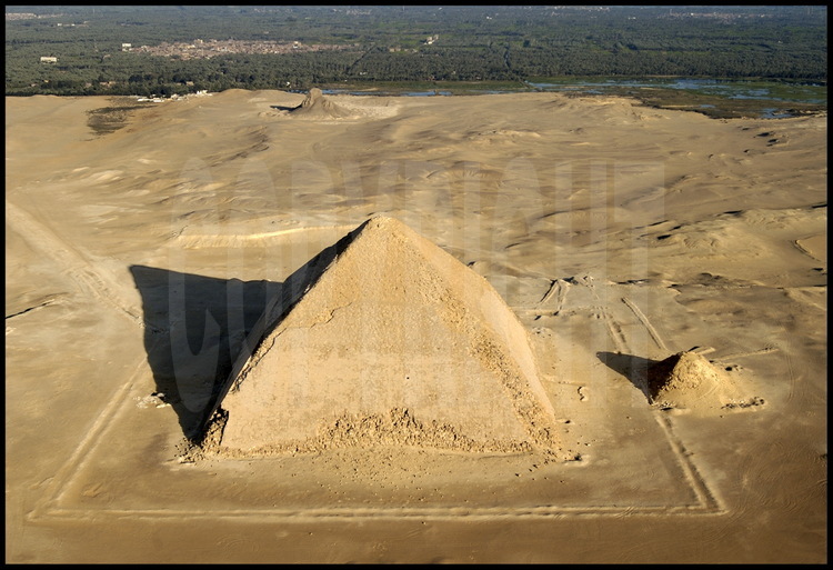 La pyramide rhomboïdale de Dashour (IVème dynastie) bâtie par Snéfrou, père de Kheops. En arrière plan, le village de Minshat Dashour et l’oasis occidental de la vallée du Nil et le site ou était située Memphis, l’ancienne capitale des Pharaons de l’ancien Empire.