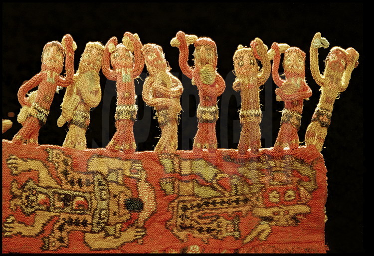 Futur musée de Nazca, ville de Nazca, Pérou.
Au centre de ce manteau funéraire datant du 3ème siècle avant JC, des centaines de bonshommes, tous différents, tissés en trois dimensions. D’une hauteur de 3 centimètres chacun, ils représentent des musiciens dansants et jouant divers instruments. Le tissage Nazca demeure un mystère : on est aujourd’hui incapable de reproduire un travail de cette qualité avec des méthodes traditionnelles.