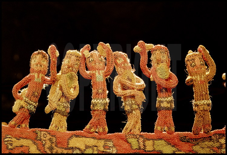 Futur musée de Nazca, ville de Nazca, Pérou.
Au centre de ce manteau funéraire datant du 3ème siècle avant JC, des centaines de bonshommes, tous différents, tissés en trois dimensions. D’une hauteur de 3 centimètres chacun, ils représentent des musiciens dansants et jouant divers instruments. Le tissage Nazca demeure un mystère : on est aujourd’hui incapable de reproduire un travail de cette qualité avec des méthodes traditionnelles.