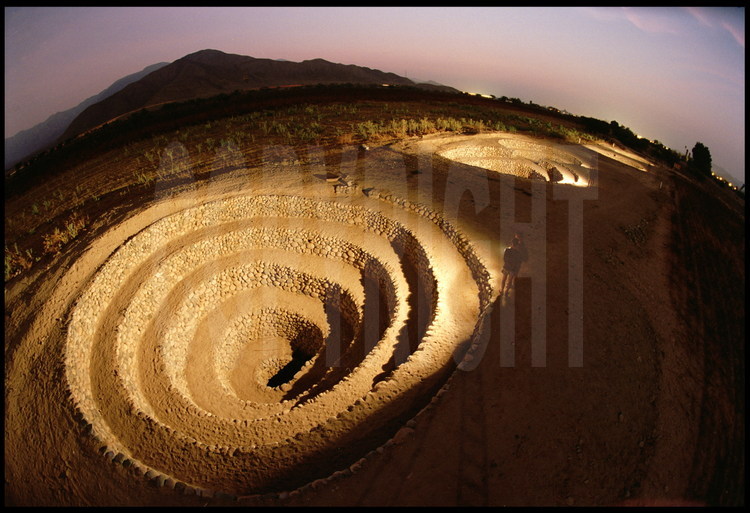 Site archéologique de Cantalloc, région de Nazca, Pérou.
Ces spirales en pierre d’une largeur de 20 mètres représentent la partie visible des vestiges de l’immense ensemble architectural des aqueducs de la civilisation Nazca. Construits sur des dizaines de kilomètres au début de notre ère, les aqueducs approvisionnaient les cités avec l’eau provenant de la Cordillère des Andes. Ces larges spirales permettaient à l’eau de s’oxygéner correctement, mais aussi d’accéder aux galeries pour leur entretien.
