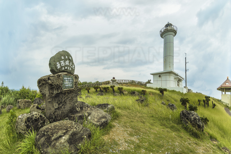Japon - Yaeyama Islands - Okinawa - Yonaguni Island : monument à la pointe Ouest de l'île, qui est aussi le point le plus occidental de tout le territoire japonais (Taiwan est à seulement 111 km). En arrière plan, le phare d'Irizaki.