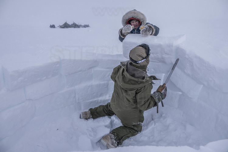 Canada - Etat du Nunavut - Opération Nunalivut 2018 - Environs de Cambridge Bay -  Camp de survie n° 1 : Les militaires apprennent à construire des igloos. L'assemblage des blocs (pas si simple) doit être théoriquement achevé en deux heures. Il peut sauver des vies en cas de problème mécanique ou de météo qui se dégrade subitement (blizzard). Ici, William Linwood (masque) et Ryan Alagohlok (capuche). // Canada - State of Nunavut - Operation NUNALIVUT 2018 - Surroundings of Cambridge Bay - Survival Camp 1: Soldiers learn to build igloos. The assembly of the blocks (not so simple) must be theoretically completed in two hours. It can save lives in case of a mechanical problem or weather that is suddenly degraded (blizzard). Here, William Linwood (mask) and Ryan Alagohlok (hood).