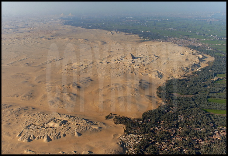 A l’ouest du ruban fertile de la vallée du Nil, vue aérienne du plateau de Sakkâra, aujourd’hui un désert d’où surgissent les vestiges du passé. Au nord, (a fond à gauche), se trouve le plateau de Gizeh avec les trois fameuses pyramides de la IV dynastie : Kheops, Khephren et Mykérinos. Puis les trois petites pyramides d’Abousir. Au centre, sur le site de Saqqarah, la célèbre pyramide à degrés de Djoser, datant de la III dynastie (plus ancien monument en pierre de l’histoire de l’humanité). Juste à droite, la pyramide de Téti, prédécesseur d’Ouserkarê. Au sud (premier plan), le complexe funéraire de Pépy Ier, fouillé par les archéologues français J. Leclant et A. Labrousse. Entre les sites de Djoser et de Pépy Ier, le site de Tabbet al-Guech où l’équipe de l’archéologue Vassil Dobrev fouille pour retrouver la trace du pharaon disparu, Ouserkarê. Malgré la sensation d’incompréhension qu’inspire pareille étendue, les archéologues perçoivent de mieux en mieux l’agencement de ces colossales nécropoles construites suivant des axes se recoupant les uns avec les autres.