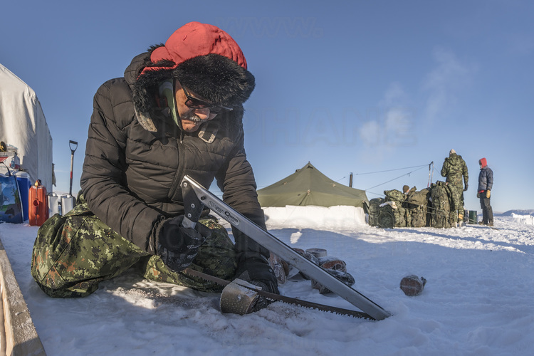 Canada - State of Nunavut - Operation NUNALIVUT 2018 - Surroundings of Cambridge Bay - Survival Camp 2, located on a bay in the Northwest Passage. Ranger Jimmy Evalik, 59, Chief Ranger of the Cambridge Bay area and leader of Camp No. 2, prepares the evening meal: freshly caught lake trout, sawn and then cut with an ax and boiled. This fish is also delicious raw.