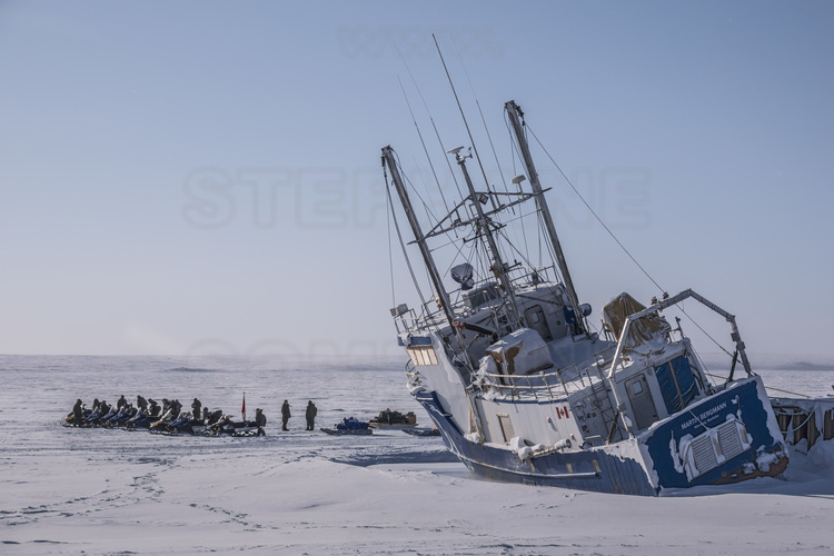 Canada - State of Nunavut - Operation NUNALIVUT 2018 - In Cambridge Bay, a snowmobile patrol meet on the shoreline of the Northwest Passage. In the foreground, the scientific boat Martin Bergmann caught in the ice.